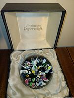 Paperweight displayed inside its original black and cream satin lined display box marked 'Caithness Paperweight'.