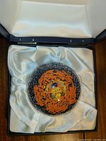 Glass sunflare paperweight in navy blue display box lined with cream satin fabric.