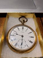 Front view of gold filled pocket watch face showing white dial with Roman numerals, subdial, and cracked glass