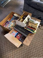 Boxes of assorted novels and books from various authors including Ian Fleming and Clive Cussler.