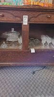 Shelf with crystal lidded serving dishes and platters, as well as various crystal glassware