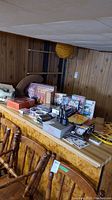 Wide view of a basement counter showing stacked boxes of board games including Monopoly, Scrabble, Clue, Risk, and Life. There are walkie-talkies, playing cards, DVDs, poker chips, and other game accessories visible on the counter.