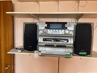 Front view of Emerson home audio system with stacked components and two speakers on sides on a shelf