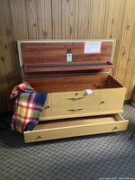 Chest open showing cedar-lined top storage with small upper shelf covered in green felt, stamped with Lane Aroma Mattress logo, and a multicolored throw inside.