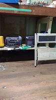 Wide view showing Xantrex Powerpack 300, Super Furnace heater, Eveready flashlight, metal step stool under a workbench.