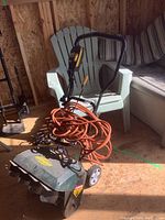 Photo showing front and side angle of Yardworks electric snow thrower with orange extension cord coiled on top.