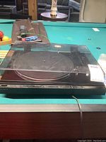 Side view of turntable with dust cover closed showing record platter and black surface