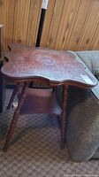 Full view of vintage wooden table showing rounded edges, surface scratches, and overall shape.
