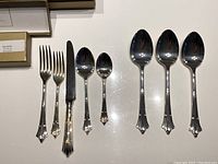 Close-up of fork, dinner knife, dessert spoon, and teaspoon from Ashley silverware set showing ornate handle design.