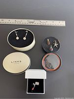 Overall layout of jewelry items with gift boxes and ruler for scale