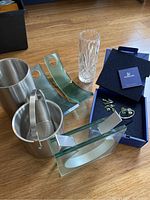 Photo showing all items: tall crystal flower vase, stainless steel vase, 2 green glass wine holders, Swarovski napkin holders in boxes, stainless steel ice bucket and wine cooler.