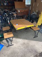 Full view of the yellow folding table set with four matching folding chairs in a garage setting, showing table surface and chair design.