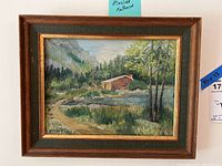Full view of the framed oil painting showing a rural landscape with a pond, trees, and a wooden building.