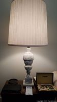 Full view of one lamp showing carved marble body and new beige fabric shade
