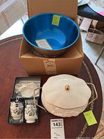 Photo of lot showing Paul Revere lidded bowl, two Royal Worcester egg coddlers in their box, and Oneida blue hollowware bowl with copper-tone exterior inside a cardboard box on a table.