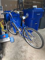 Blue Raleigh M20 mountain bike shown from left side with visible Shimano gear shift and tires with knobby tread.