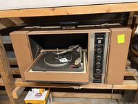 Front view of the Symphonic Skyliner B showing the open turntable with tonearm and platter, control knobs on the right panel, and the handle on top.