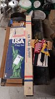 Photo showing the boxed USA Flag Set and U.S. Flag Outfit box on a table with other items around them
