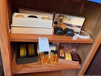 Two-shelf overview of assorted grooming items including soap boxes, cologne bottles and accessories
