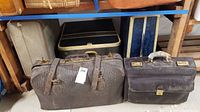 Five pieces of vintage luggage including leather suitcases and hard cases with wear and dust.