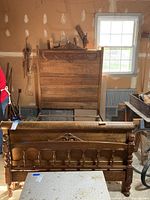 Front view of the oak sleigh bed showing the tall paneled headboard with carved decorative motif.