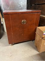 Front view of the closed mahogany record cabinet with brass handles, showing wood grain and rectangular form.