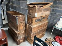 Stacked nine antique wooden WWII-era military crates showing varying condition and broken lid boards, dark stained wood with metal reinforcements.
