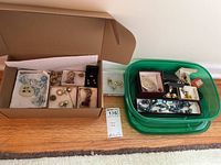 Overview of costume jewelry items including pins, earrings, and beads arranged in boxes and containers