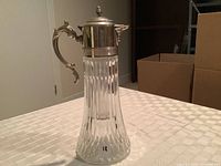 Full view of the antique silver and glass jug showing the fluted glass body, silver lid, and handle.