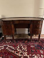 Front view of kidney-shaped desk showing seven drawers and brass gallery rail