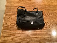 Front view of black leather purse showing structured shape and handles.