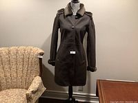 Full front view of the dark brown Danier leather coat displayed on a mannequin, showing button closure and plush hood and cuffs.