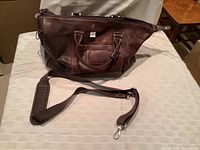 Image showing the full dark brown genuine leather tote bag with shoulder strap detached and placed in front, photographed on a light surface.