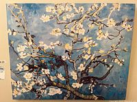 Front view of a gallery stretched canvas print featuring dark branches and white blossoms on a blue background.