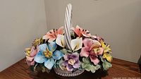 View of entire Capodimonte floral basket showing colorful flowers and white twisted handle basket base.
