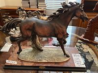 Side view of the brown patinated horse sculpture on wood base