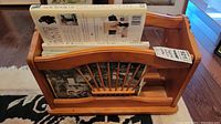 Photo of wooden newspaper rack holding hardcover books, showing the front side with spindle design.