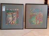 Two framed pastel artworks signed by artist Vatche, each featuring abstract forest scenes in vibrant colors, displayed side by side on the floor.