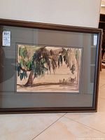 Framed watercolor painting showing a tree with hanging foliage in earthy tones, mounted on a gray matte in a dark wooden frame.