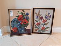 Two framed floral tapestries side by side on floor showing overall appearance and size