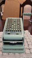 Front view of vintage Paymaster adding machine showing keypad layout and brand label at base.