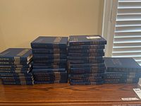 Stacks of blue hardcover books including World Book Encyclopedia volumes, World Book Yearbooks, a dictionary, and Roget's II The New Thesaurus.