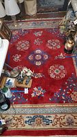 Full rug view in red with floral patterns and beige bordered edges, showing the entire 8'x10' size.