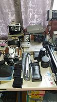Overall view showing all cameras, tripod, GPS unit, cases and manuals on table