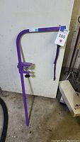 Full view of the purple metal dog grooming arm bar with clamp and attached strap, showing overall condition and structure.