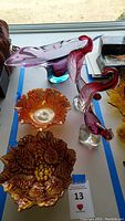 Photo showing large purple and blue modern art vase, two carnivals glass bowls in amber and red/gold, two Italian glass bird figurines, one bird with damage