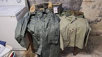 Overview of green flight coverall and two military shirts on wooden table