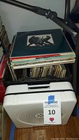 Stack of vinyl records in crates with Ion turntable closed in front