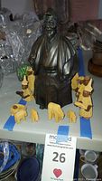Front view of the bronze Asian man figure surrounded by multiple small hand-carved wooden nativity figures including several people and animals
