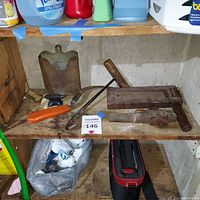 Overview of lot on wooden shelf showing the primitive wooden noise maker, small anvil, copper mailbox, ice grip, wooden mold/clamp, and a long cylindrical wooden tool.